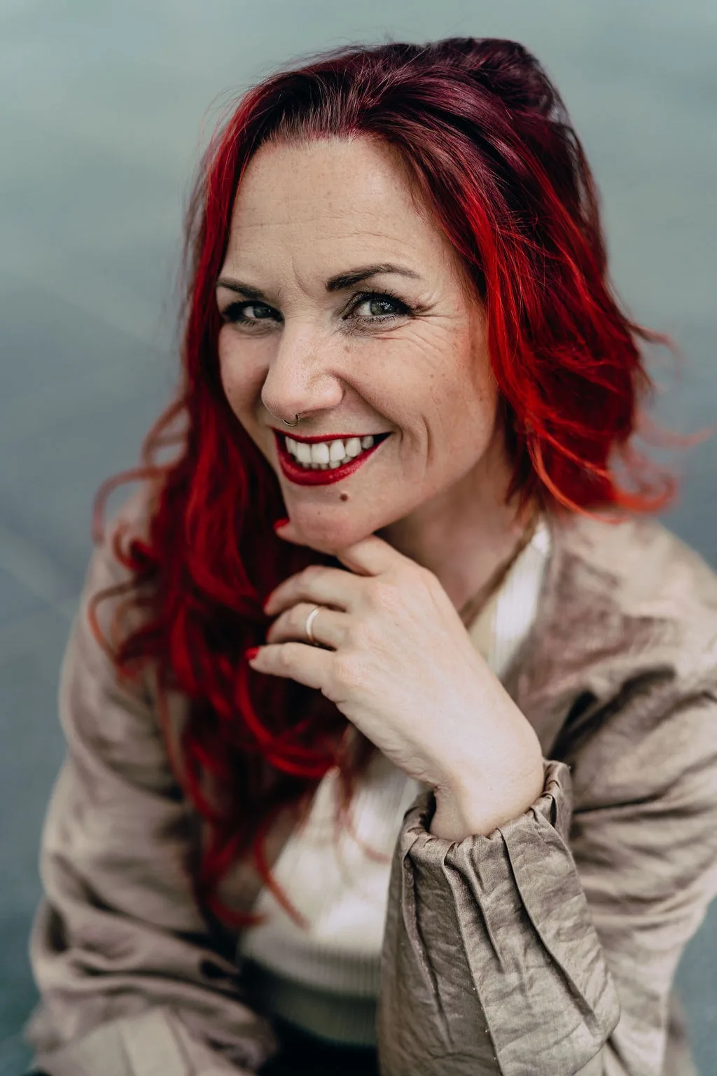 Sabrina Amels, Personal Brand Designerin und Gründerin vom Brand Atelier, mit der Hand am Kinn und einem offenen Lächeln